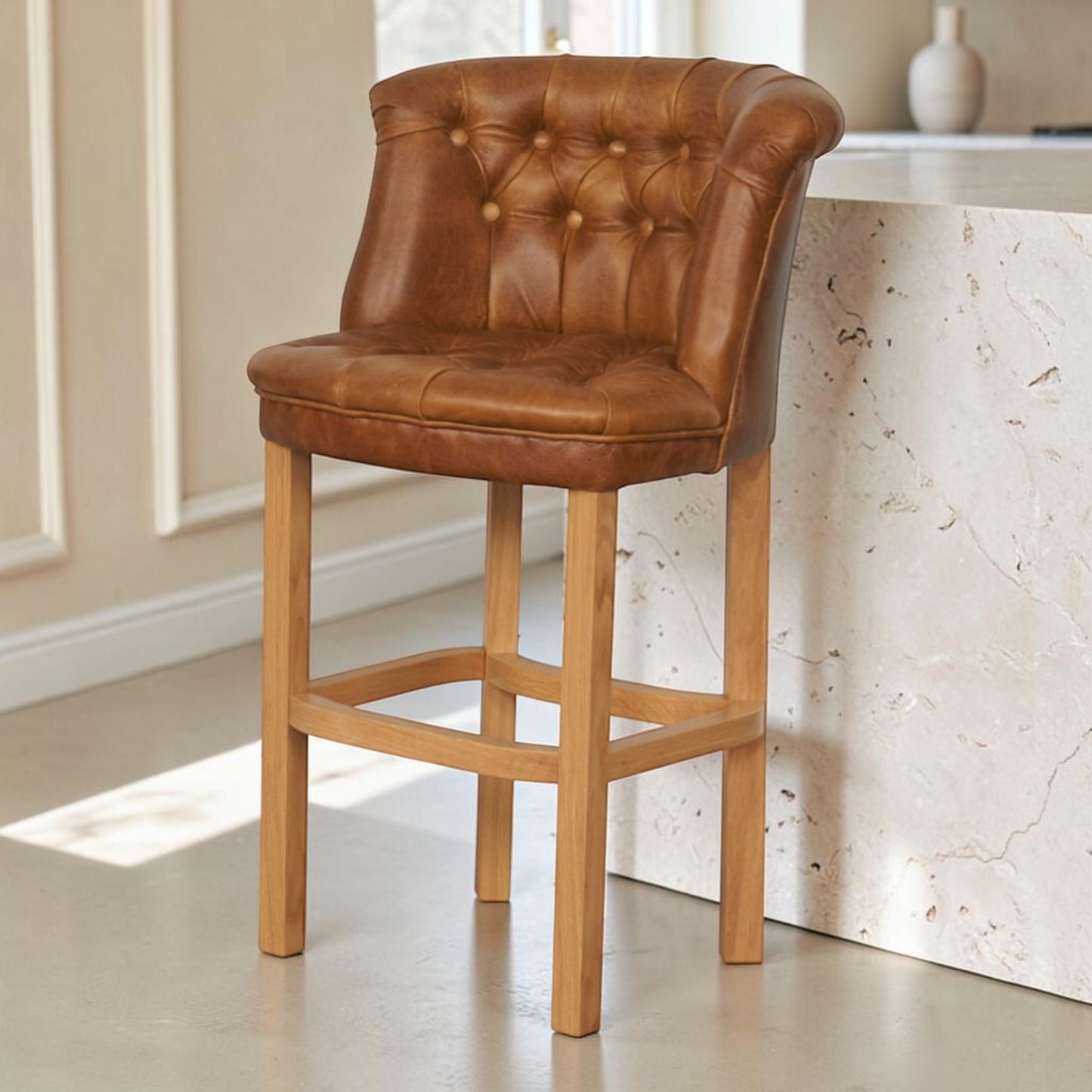 Keswick Cerato Brown leather bar stool with deep-buttoned back and solid wooden frame beside a kitchen island