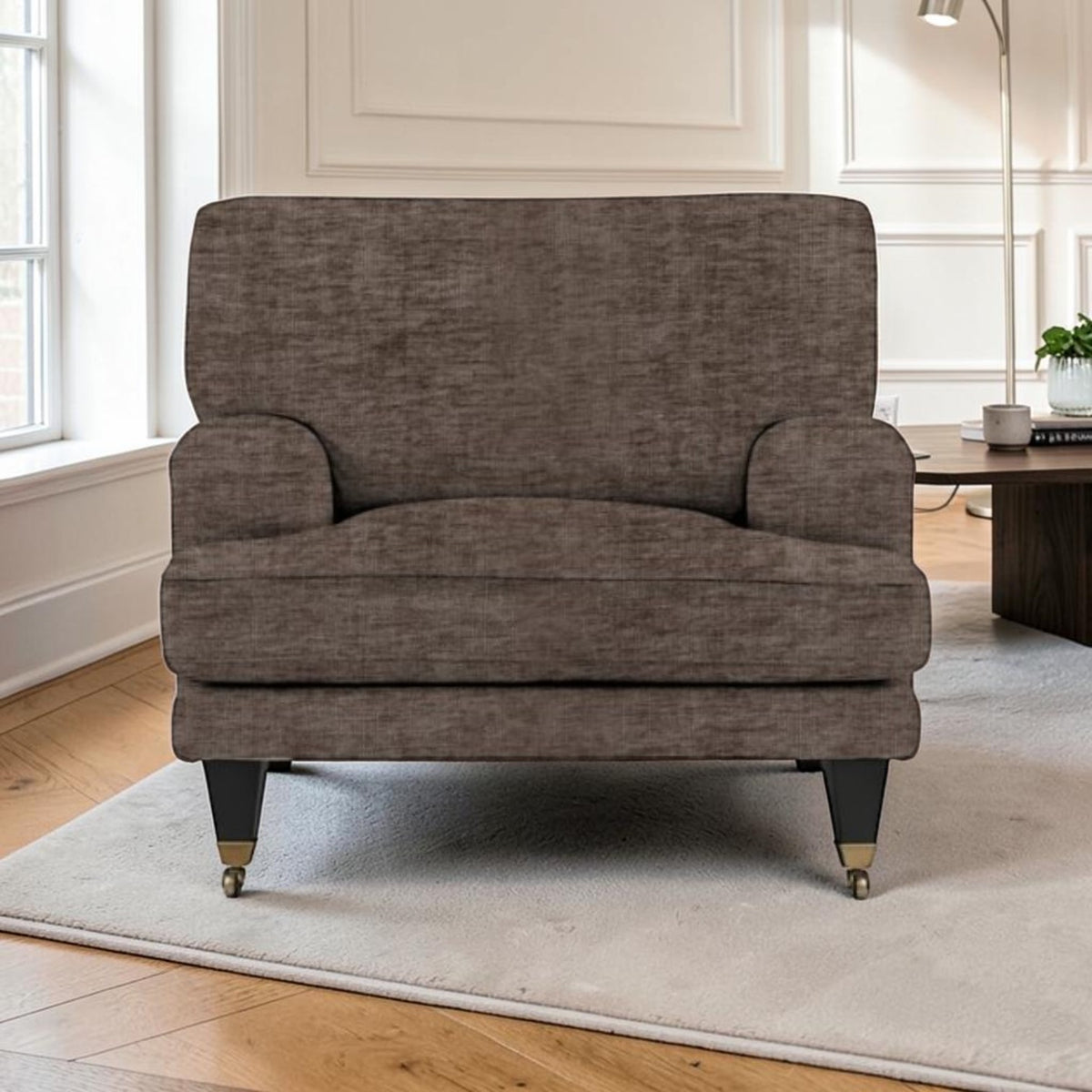 A single upholstered armchair in textured taupe-brown fabric, shown in a bright living room setting on a light rug with wood flooring and a side table in the background.