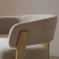 Beige upholstered chair with wooden armrest and legs against a neutral wall.