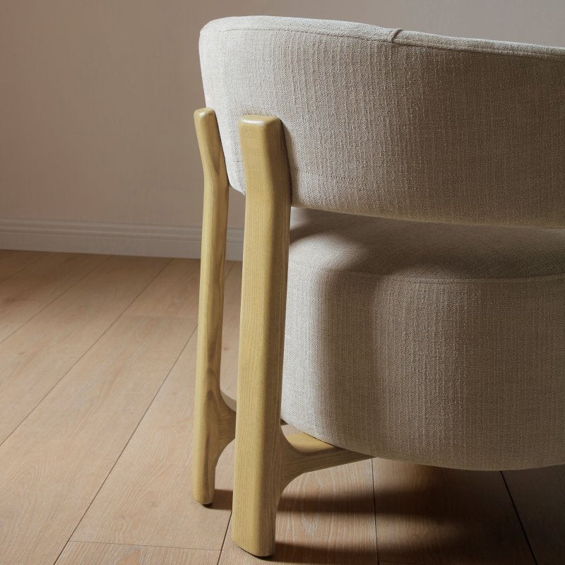 Beige armchair with wooden legs on a wooden floor.