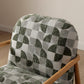 Chair with a patterned green and gray cushion on a wooden floor.