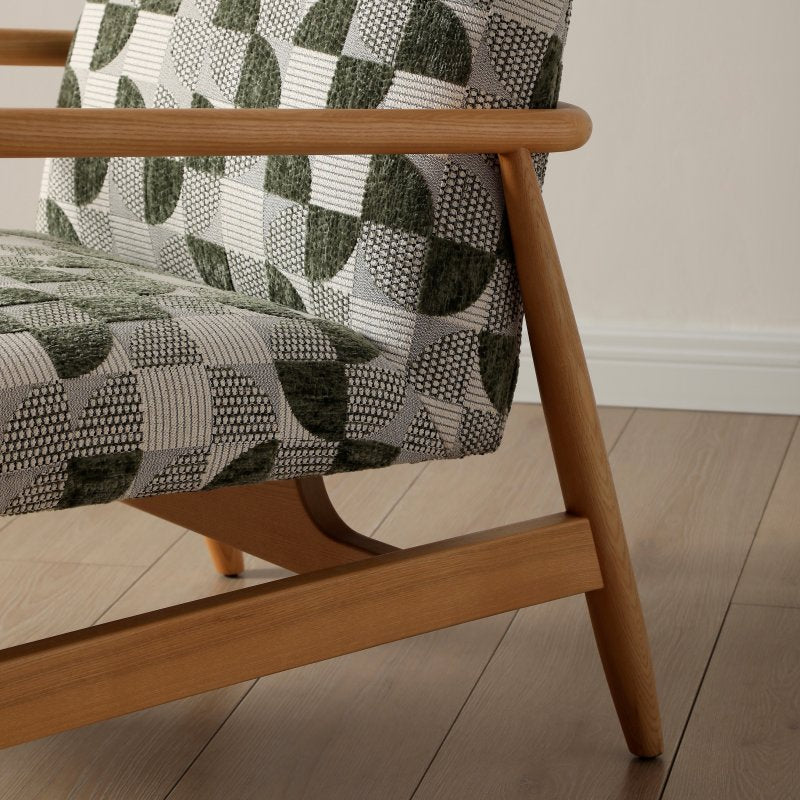 Close-up of a wooden chair with patterned fabric on a wooden floor.