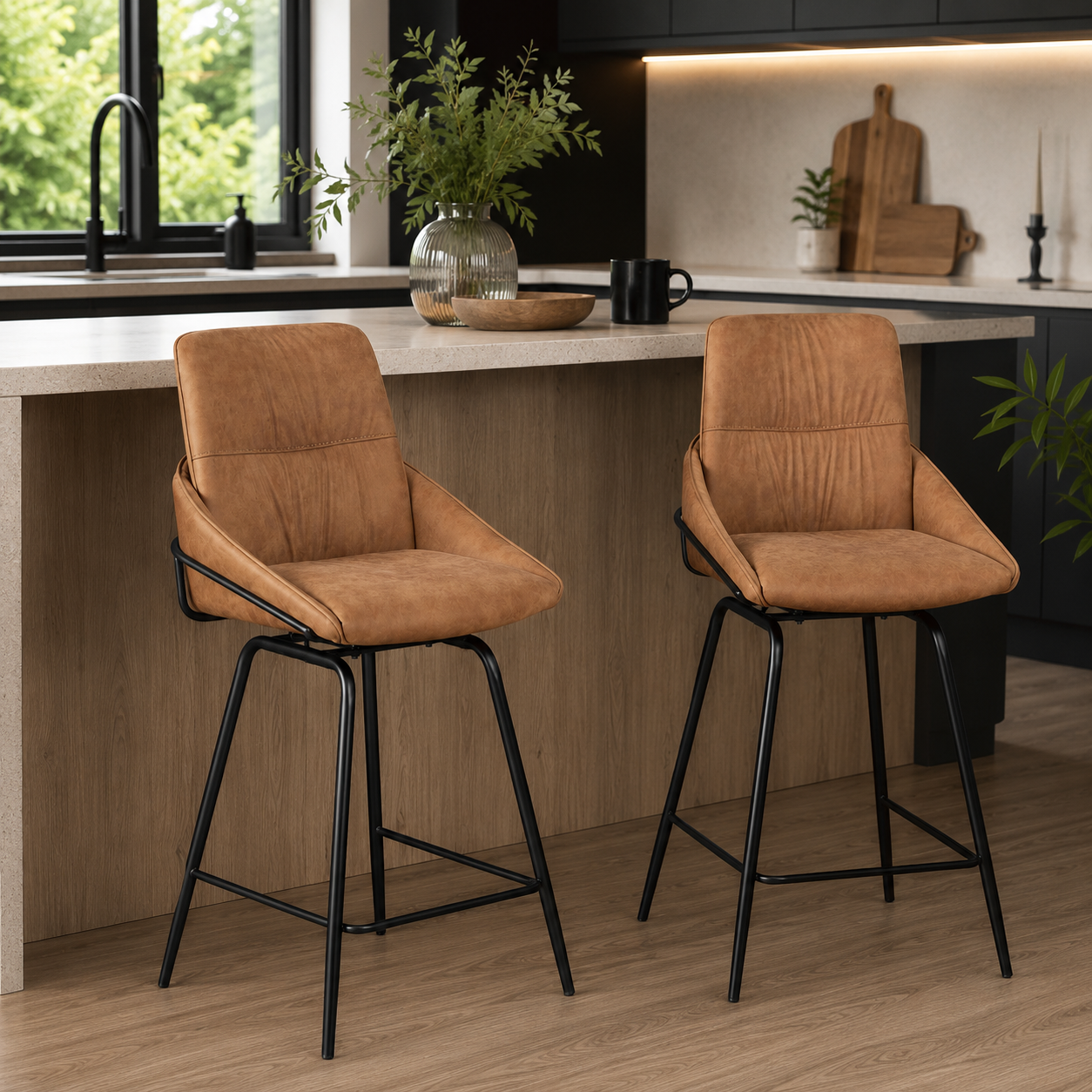 Two modern bar stools with tan leather-like upholstered seats and black metal legs, shown in a real kitchen setting with a countertop, sink, and cabinetry.