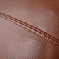 Close-up of a brown pebbled leather surface with a stitched seam running diagonally across the frame.
