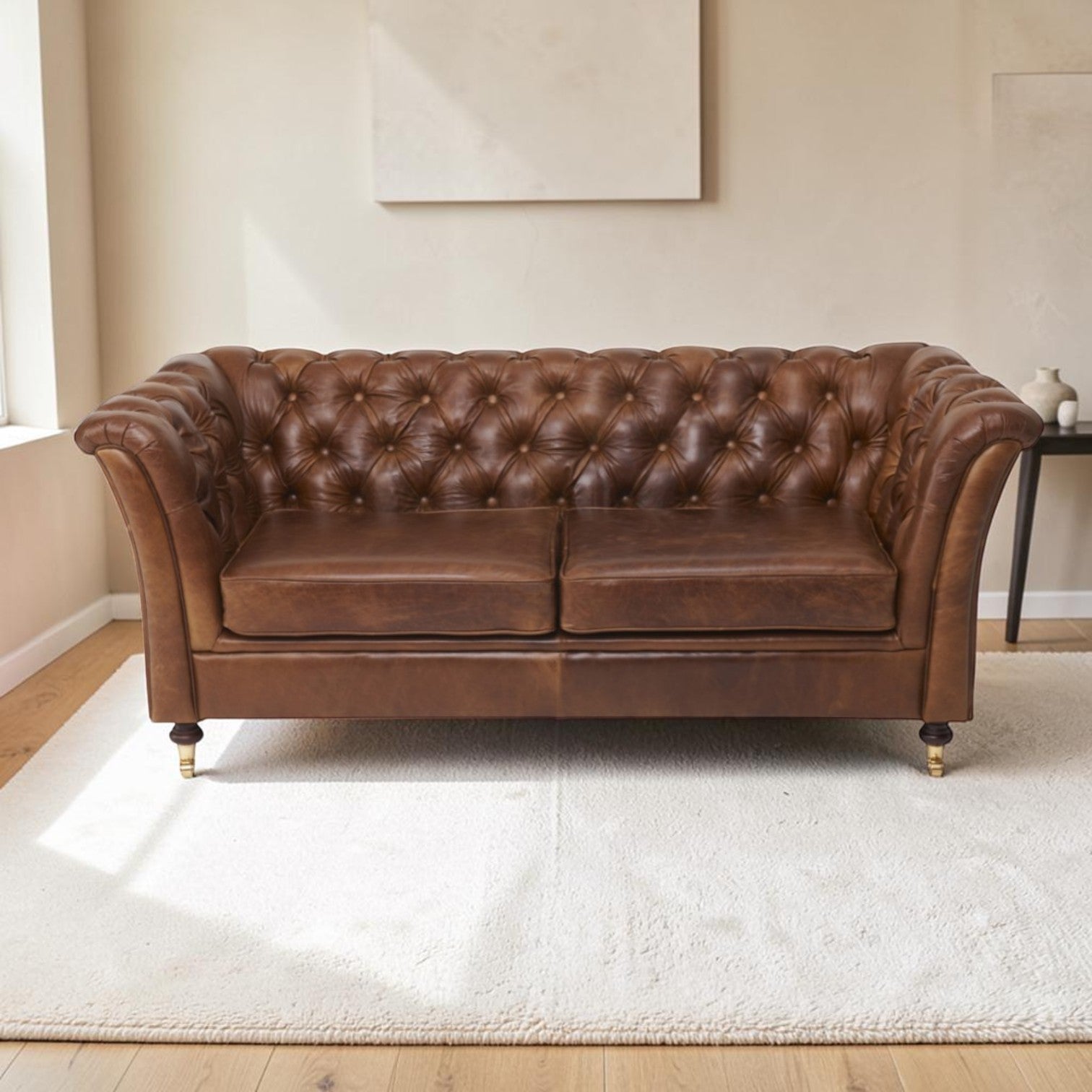 A Cerato brown leather Chesterfield sofa with tufted button detailing, shown in a bright living room setting on a white rug.