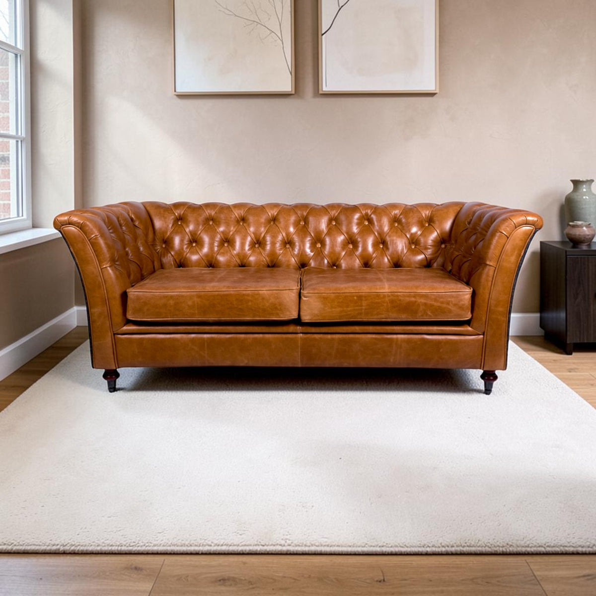 A classic Chesterfield sofa upholstered in warm Cerato brown leather, set on a large off-white rug in a living room with wood floors and neutral walls.