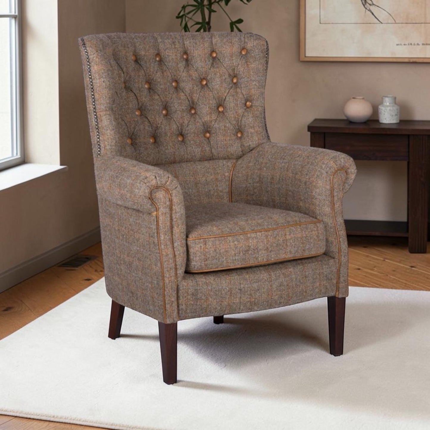 A classic wingback armchair upholstered in a textured brown and beige tweed fabric, featuring button tufting on the backrest, rolled arms, and dark wooden legs, set in a living room environment.