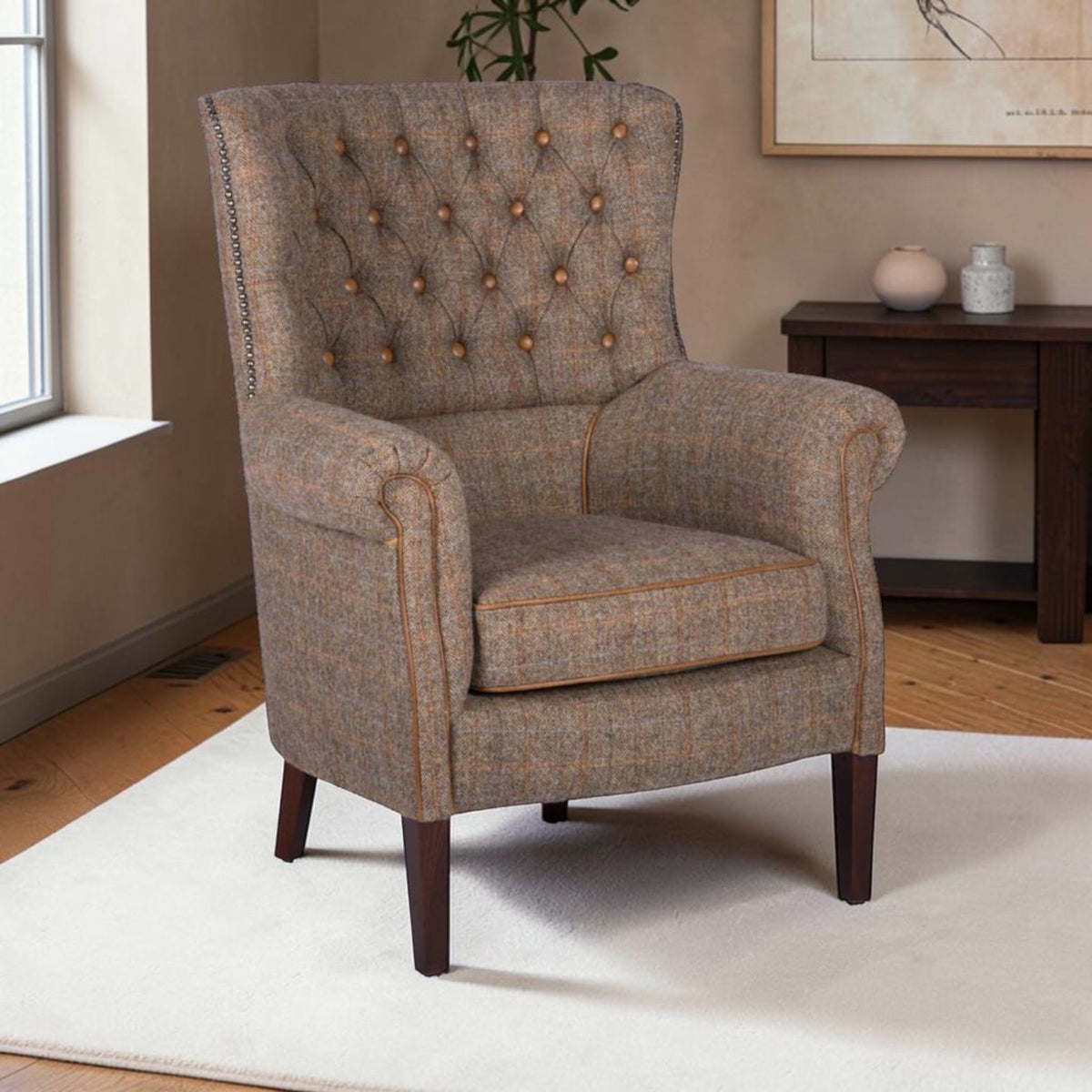 A classic wingback armchair upholstered in a textured brown and beige tweed fabric, featuring button tufting on the backrest, rolled arms, and dark wooden legs, set in a living room environment.