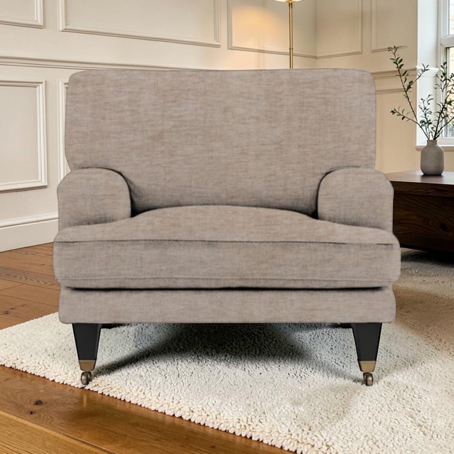 A light beige upholstered armchair with dark legs, shown in a styled living room setting on a white shag rug.