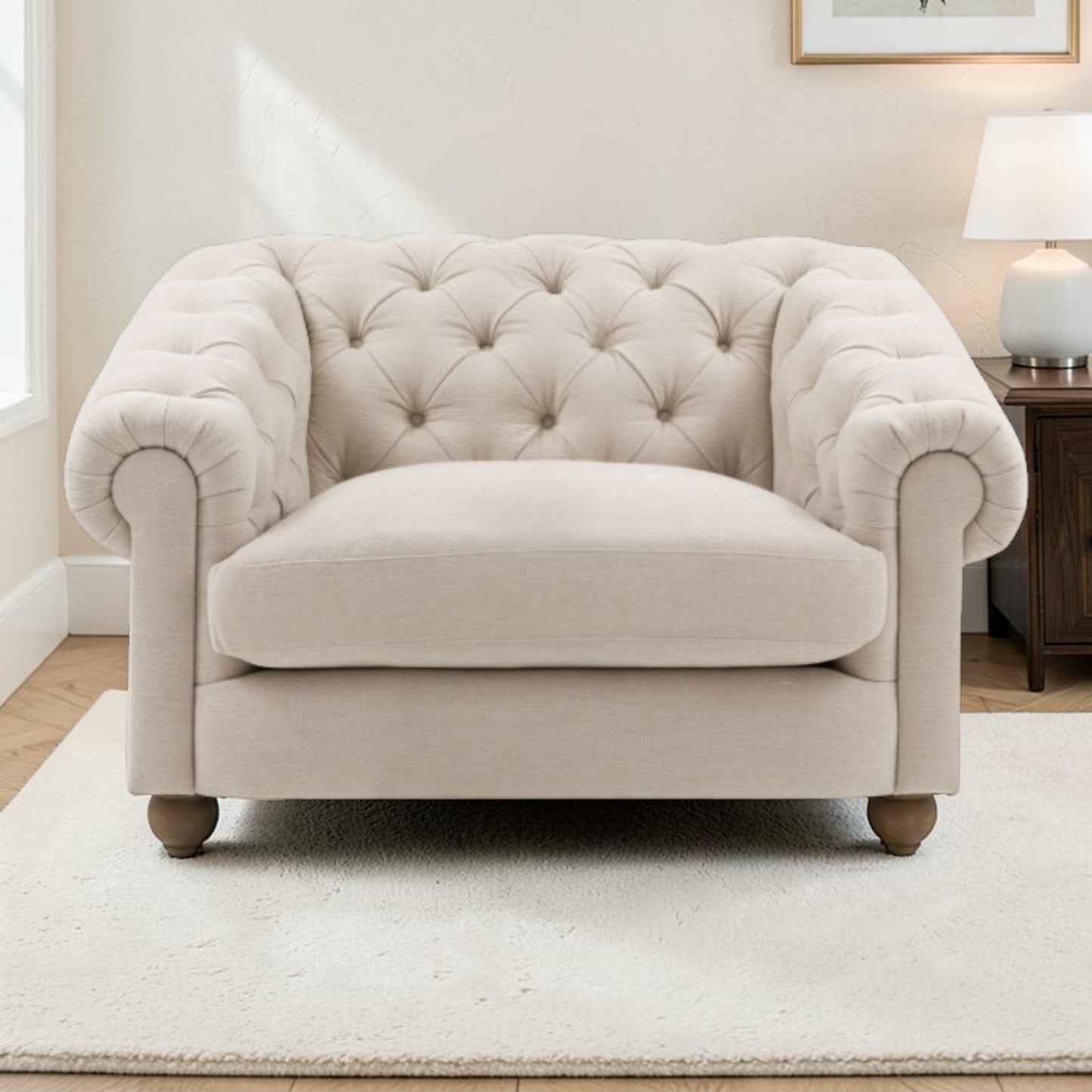A classic Chesterfield armchair in a light beige fabric, featuring deep button tufting on the backrest and rolled arms, set on a white rug in a bright, modern room.