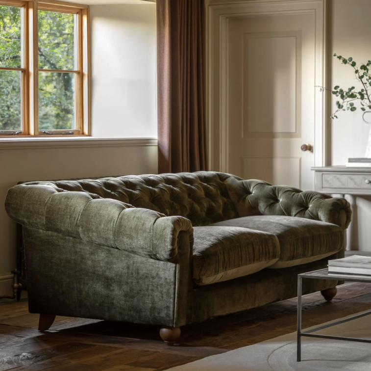 Green sofa in a room with a window and door.