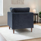 A back view of the Henley modern armchair upholstered in textured Charcoal fabric fabric with tapered wooden legs, shown in a styled living room setting on a white rug next to a side table.