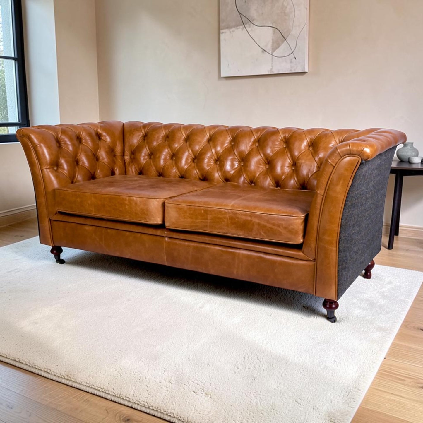 A classic Chesterfield sofa in warm tan leather with aUist Harris Tweed side panel, positioned on a white shag rug in a modern living room setting.