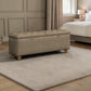 A rectangular upholstered storage bench with tufted top and turned wooden legs, shown in a styled bedroom setting on a light rug.